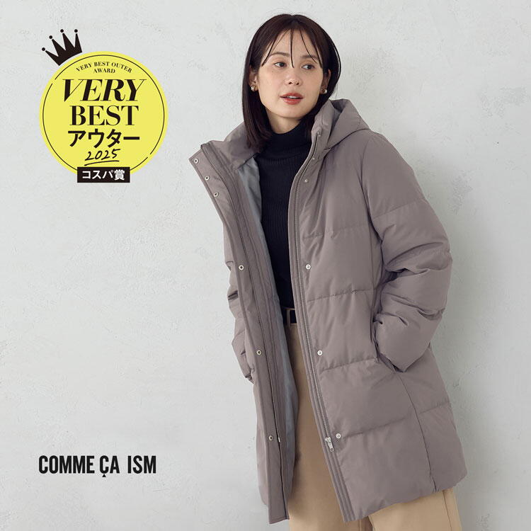 コムサイズム　黒いニットにグレーのダウンコートを羽織り、ベージュのズボンを履いた女性の写真